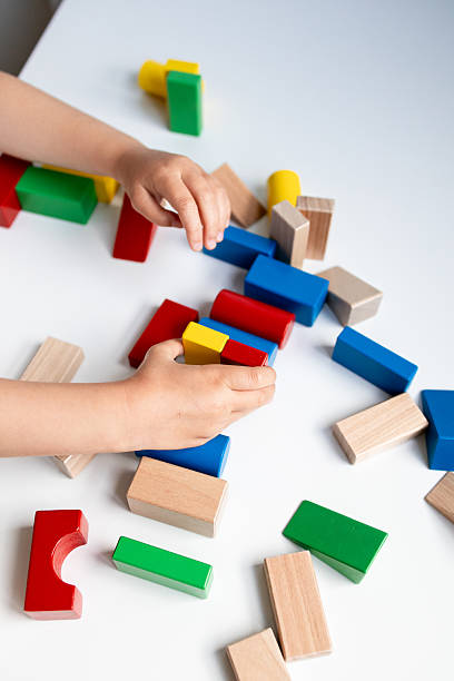 istock Child playing with colorful wooden building blocks on white surface 2216646746