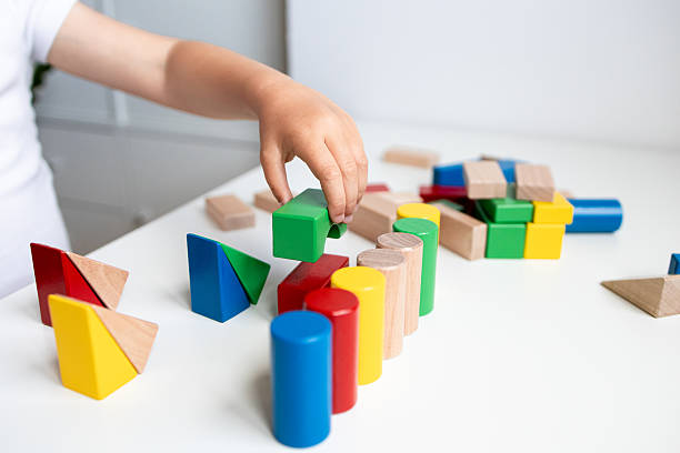 istock Child playing with colorful geometric wooden blocks on white surface 2216647090