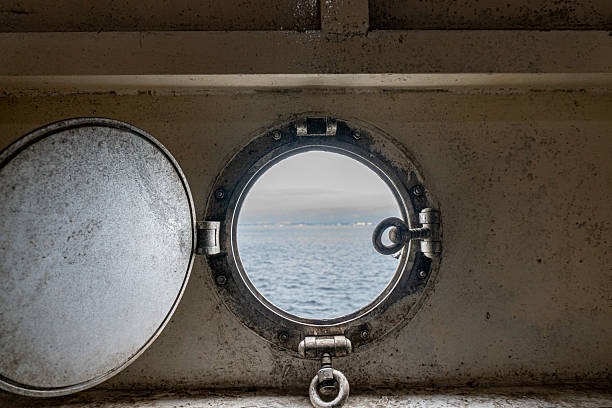 Porthole view to calm ocean and distant icebergs.