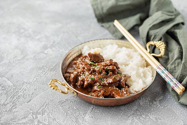 Homemade Korean Beef Bulgogi BBQ with Sesame Seeds and Scallion and rice in skillet