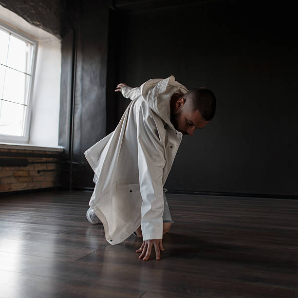 istock Stylish young dancer man in trendy clothes with jacket and jeans performs in a dark dance class 2216655522