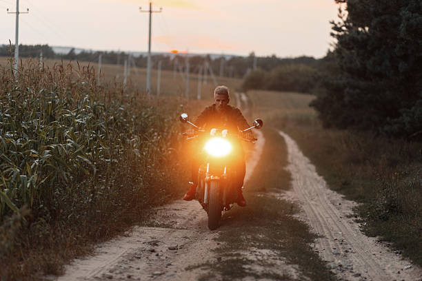 istock Man traveler riding a motorcycle with light in the field 2216655703