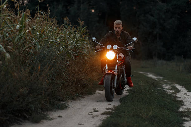 istock man is riding a motorcycle with light in a cornfield in the evening 2216655708