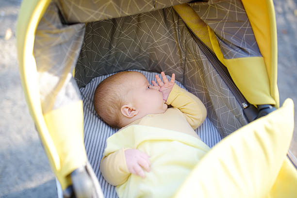 Newborn baby sucks his thumb and falls asleep. Cute 2 month old baby sleeping in stroller. Sweet newborn boy or girl. Hungry or tired baby falls asleep with a finger in his mouth instead of a pacifier