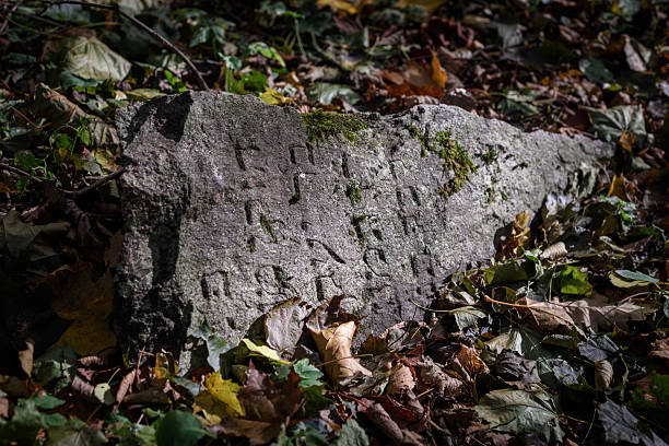 istock An ancient gravestone with Hebrew text carved into it in a ray of sunlight. 2216658996