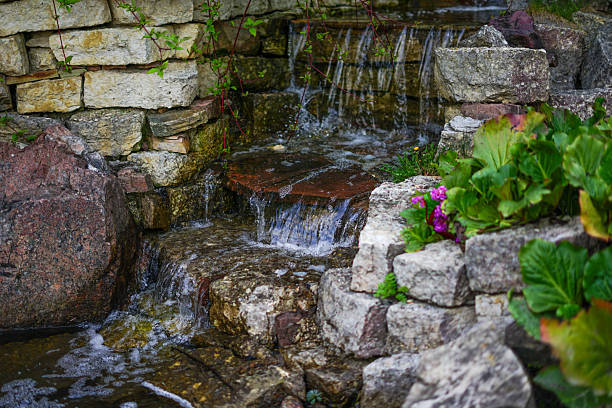 istock Waterfall cascading over stone rocks in a lush garden 2216664123