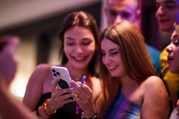 istock Group of Friends Smiling While Using a Smartphone at a Social Gathering 2216664291