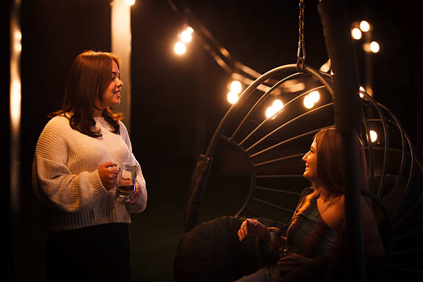 Two friends enjoying an evening conversation outdoors with warm lighting
