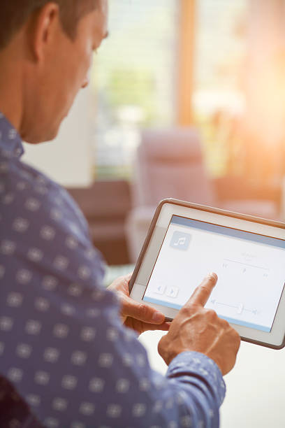 istock Man using smart home automation in living room with digital tablet 2216670374