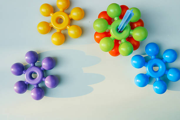 Colorful plastic construction toys with circular arms scattered on a white background. A toddlerâs hand reaching out to touch them, evoking creativity and early learning through play.