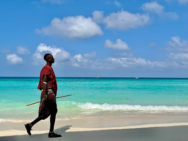Zanzibar, Tanzania - January 02,2024: Maasai warrior dressed in traditional clothes on sand beach of Zanzibar island.