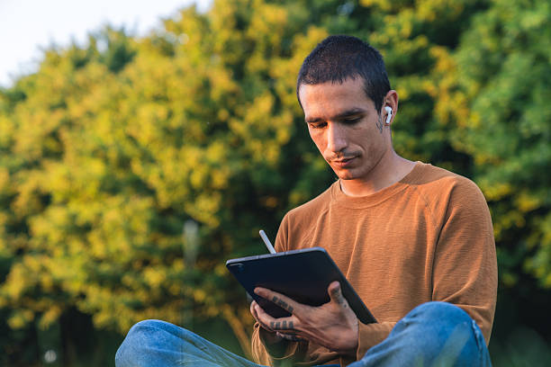 istock Young man drawing on tablet in the park 2216681140
