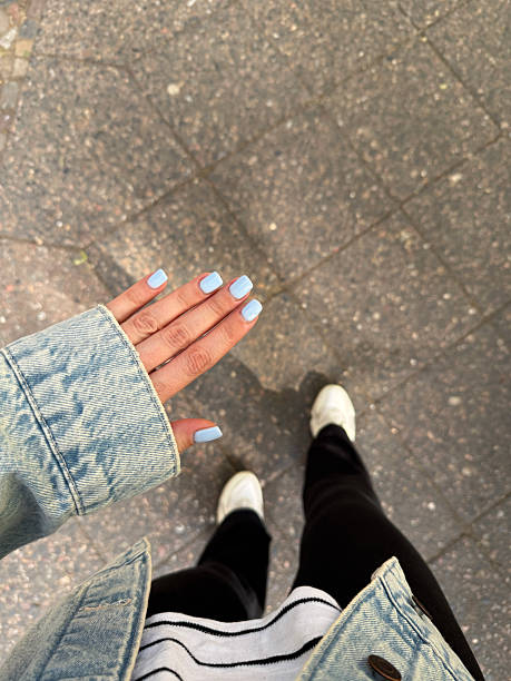 Woman showing her light blue painted nails while walking down the street