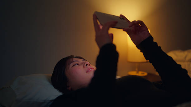 istock Woman using her mobile smartphone in dark room in her bed 2216688430