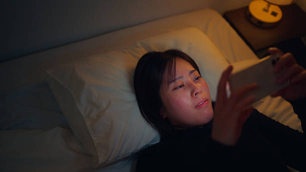 istock Woman using her mobile smartphone in dark room in her bed 2216688455