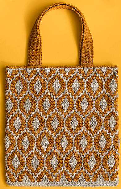 istock Modern orange grey crochet shopping bag with mosaic pattern on a yellow background. 2216689460