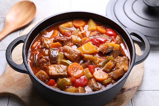 Delicious stew with vegetables in pot on light textured table, closeup