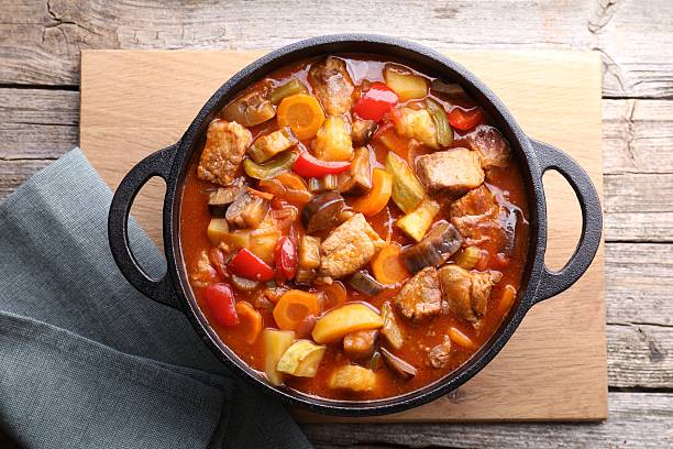 istock Delicious stew with vegetables in pot on wooden table, top view 2216689572