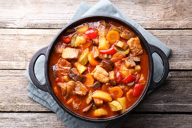 istock Delicious stew with vegetables in pot on wooden table, top view 2216689601