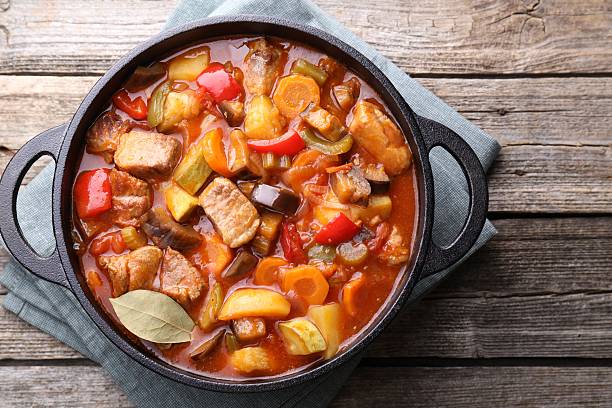 istock Delicious stew with vegetables in pot on wooden table, top view 2216689644