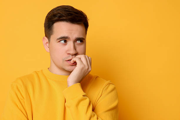 istock Portrait of scared young man on orange background, space for text 2216693025
