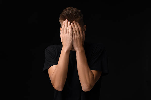 istock Portrait of scared young man on black background 2216693193