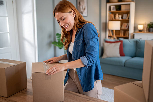 istock Smiling woman packing boxes in living room 2216693346