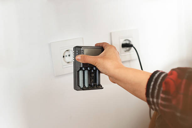 Young woman plugging in a battery charger. Unrecognizable Caucasian female.