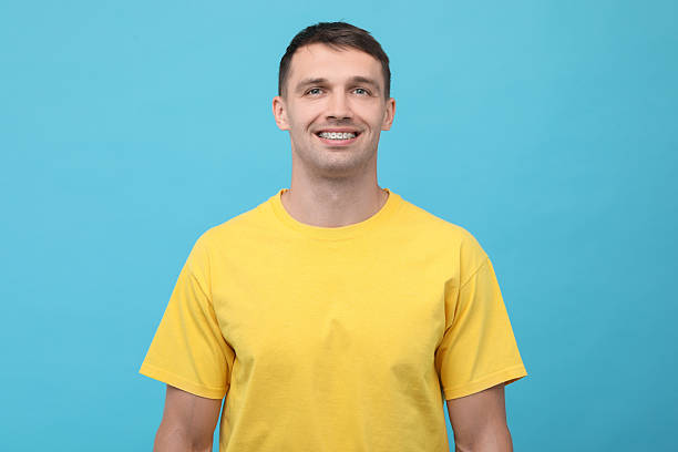 istock Smiling man with dental braces on light blue background 2216695809