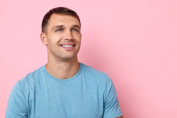 istock Smiling man with dental braces on pink background. Space for text 2216696242