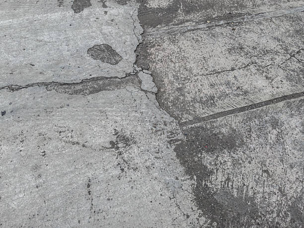 istock Cracked and scratched concrete road surface 2216696799