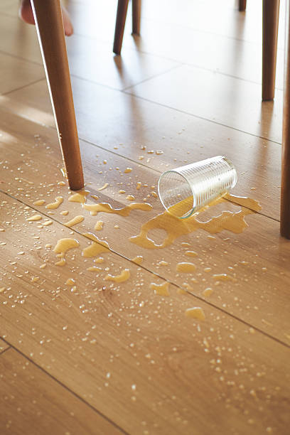 istock Cup spills orange juice on wooden floor beneath a dining table 2216696989