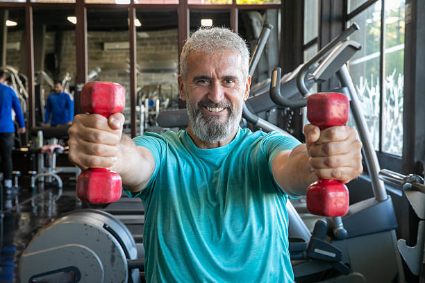 istock Senior man with barbells in gym 2216698561