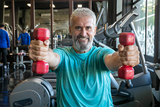 istock Senior man with barbells in gym 2216698562