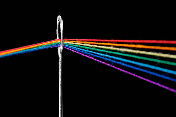istock multi-colored threads for sewing in the form of a rainbow pass through an antique needle on a black background 2216701788