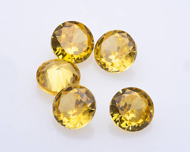 istock Five round cut citrine gemstones are arranged on a white surface, showcasing their faceted brilliance and warm yellow hue in studio lighting 2216702353