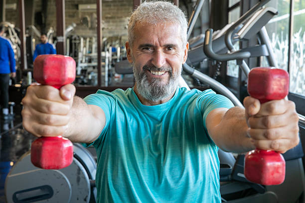 istock Senior man with barbells in gym 2216702924