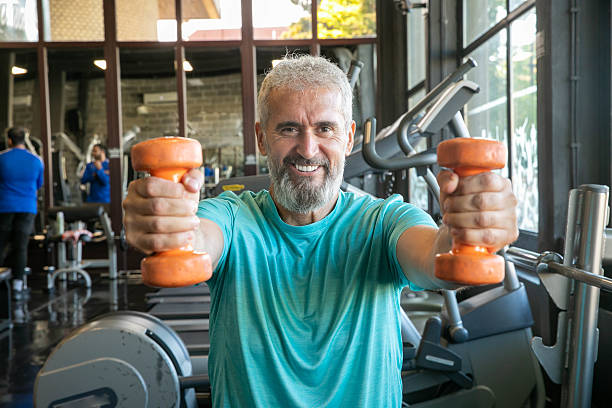istock Senior man with barbells in gym 2216703197