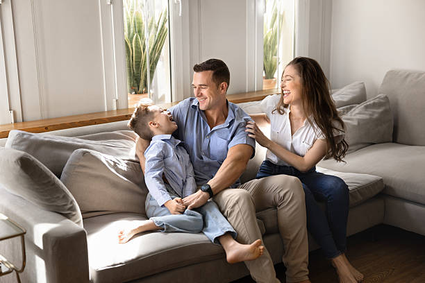istock Happy young parents cuddling kid on home sofa 2216704113
