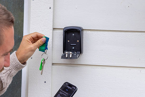 istock Man Accessing Key Safe on House Wall with Smartphone 2216707170