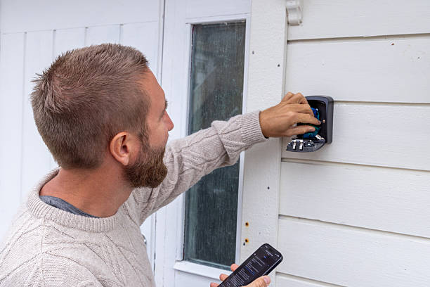 istock Man Accessing Key Safe on House Wall with Smartphone, Vacation Rental 2216707172