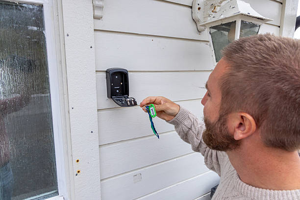 istock Man Unlocking Wall-Mounted Key Safe by Door 2216707506