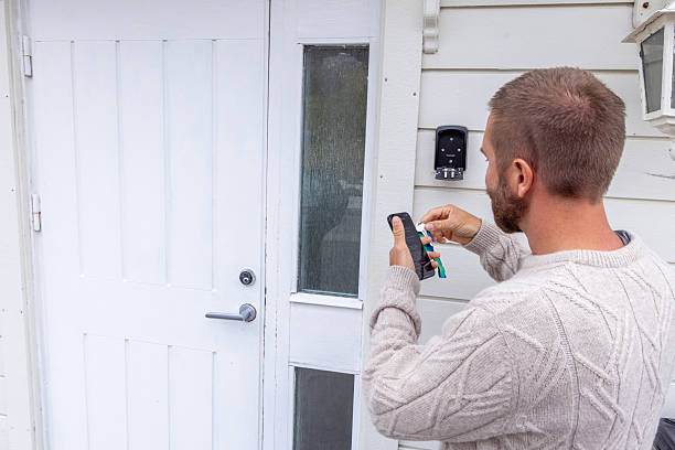 istock Man Accessing Key Safe on House Wall with Smartphone 2216707546