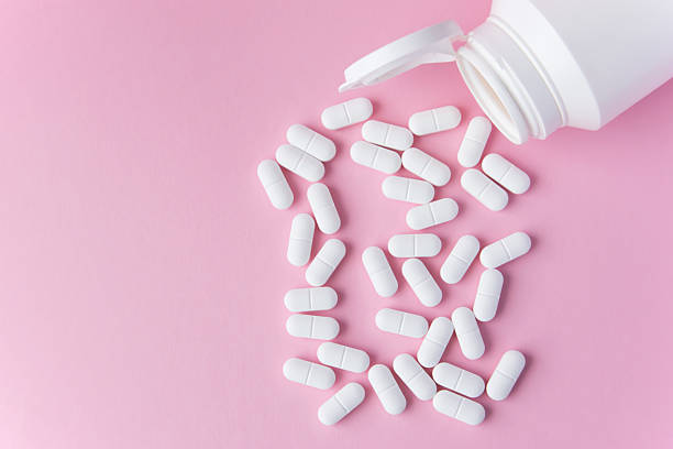 istock White tabletts or pills on the pink background with place for text. 2216710753