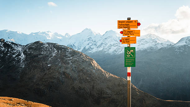 Trail sign on mountain pass above snowcapped mountain and ranges, Engadine,  Graubunden Canton, Swiss Alps
