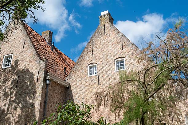 Charming dutch house showcasing traditional brickwork, tiled roof, and architectural details under a blue sky