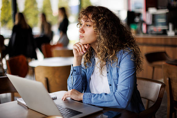 istock Young thoughtful woman working on her laptop in a cafe 2216717630