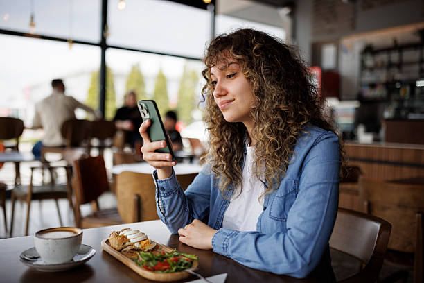 Relaxed morning routine  young woman checking her phone while enjoying brunch
