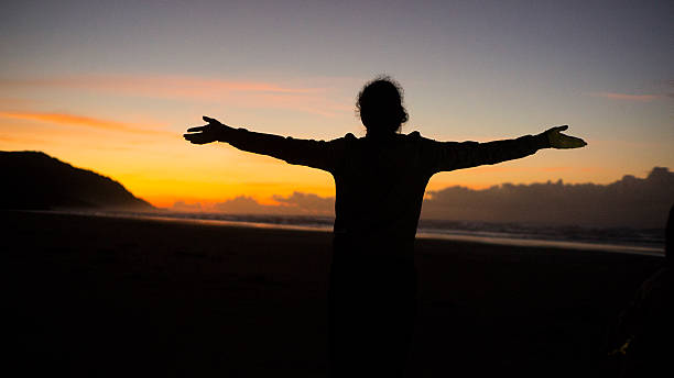 istock Silhouette Stretching on Beach at Sunrise with Orange Sky 2216719834