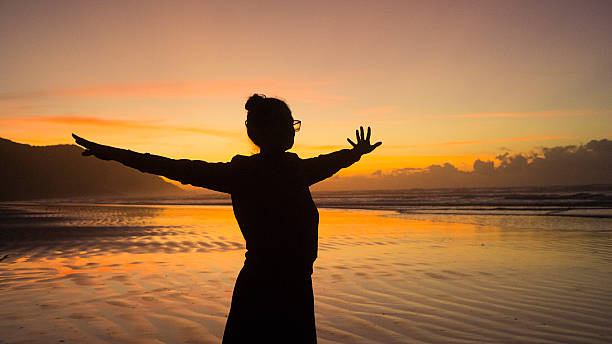 istock Silhouette Stretching on Beach at Sunrise with Orange Sky 2216720004